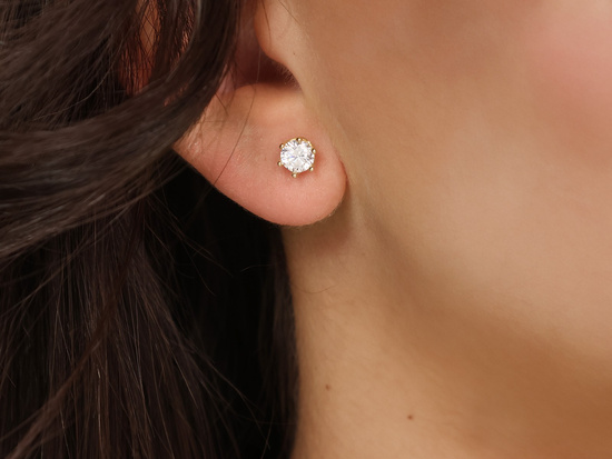 Złote kolczyki na sztyfcie z cyrkonią przy uchu