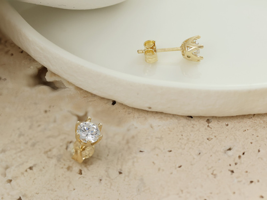 Złote kolczyki na sztyfcie z cyrkonią przy uchu