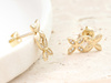 Złote kolczyki dwa kwiatki na sztyfcie przy uchu