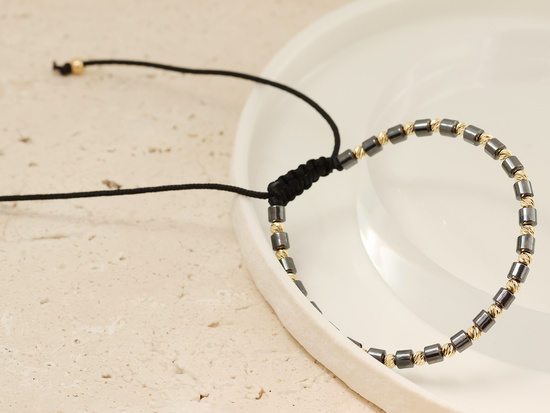 Bransoletka złote kulki i walcowate hematyty na czarnym sznurku