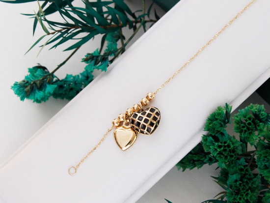 Złota bransoletka z kulkami z wiszącymi sercami z czarną emalią