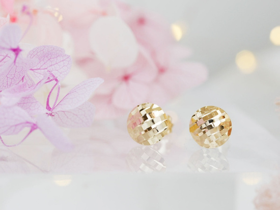 Kolczyki złote okrągłe błyszczące na sztyfcie pinezki przy uchu