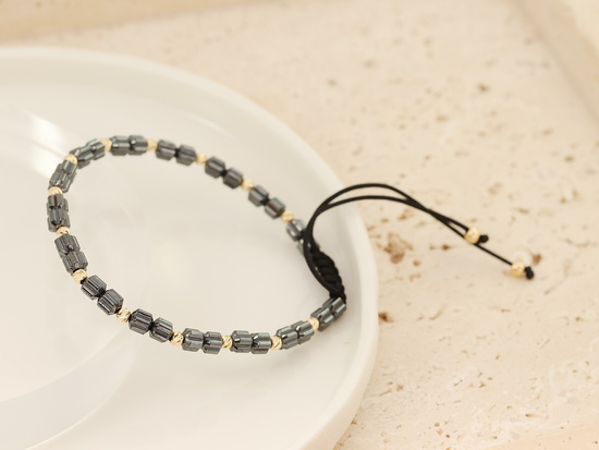 Bransoletka hematyty i złote kulki na czarnym sznurku