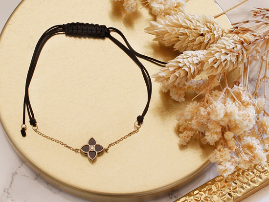 Bransoletka złoty kwiatek z czarnymi kamieniami na czarnym sznurku