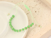 Zielona bransoletka sznurkowa ze złotymi kulkami